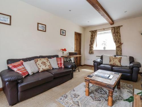 a living room with a leather couch and a coffee table at Croft Granary in Stillington