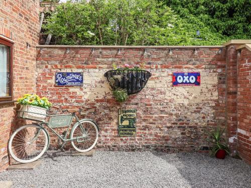a bike parked against a brick wall with signs on it at Croft Granary in Stillington