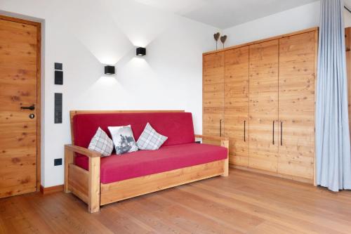 a red couch with pillows on it in a room at Ansitz Röfen in Burgusio
