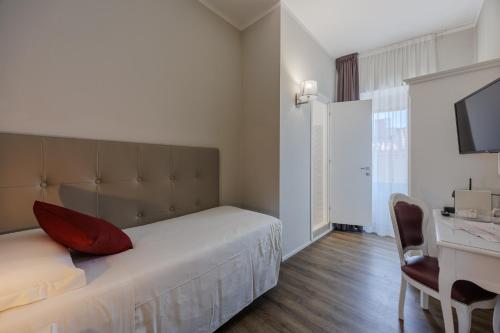 a bedroom with a bed with a red pillow and a desk at Hotel Degli Oleandri in Sirmione