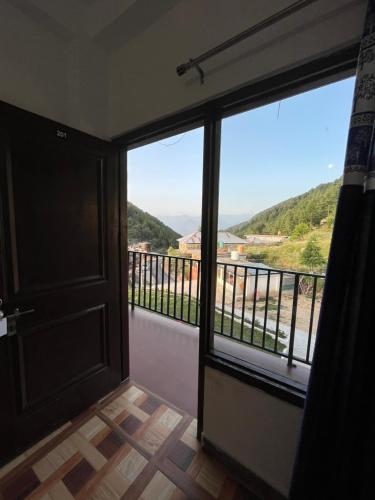 a room with a door and a balcony with a view at Sunset Lagoon Dalhousie in Dalhousie