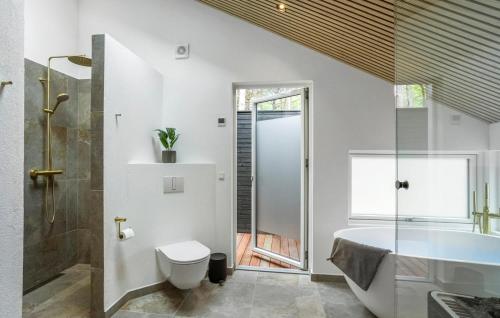 a bathroom with a tub and a toilet and a sink at Stunning Home In Nexø With Sauna in Neksø