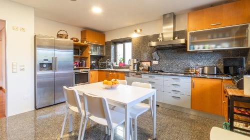 a kitchen with a white table and a stainless steel refrigerator at Com o Douro à vista in Jovim