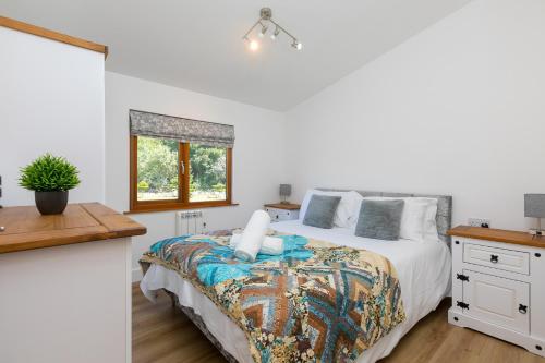 a white bedroom with a bed and a window at Costentyn, Tor Down Quarry in Bodmin