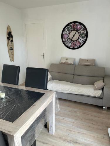 un salon avec un canapé et une horloge au mur dans l'établissement Jolie maison les pins et la mer pour 4 personnes, à Marennes