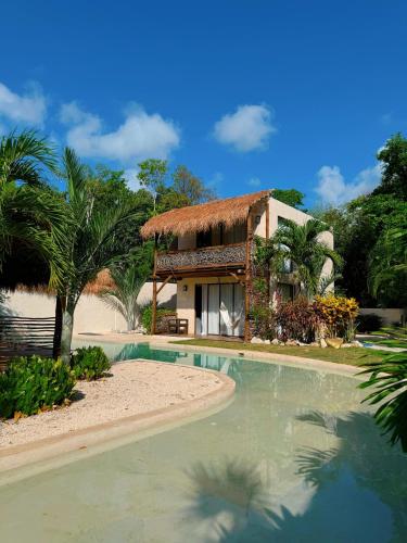 a resort with a swimming pool in front of a house at Villa AHAL, in Chemuyil