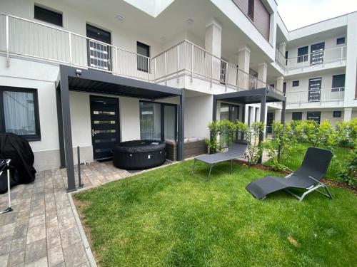 an apartment patio with two chairs and a grill at Norah Apartman - Fonyód Liget Residence in Fonyód
