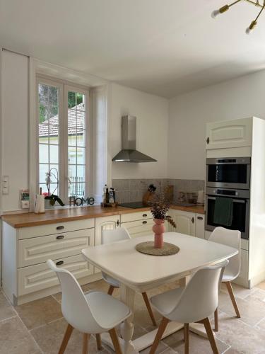 une cuisine blanche avec une table et des chaises blanches dans l'établissement Maison style Haussmannien centre ville, à Gray