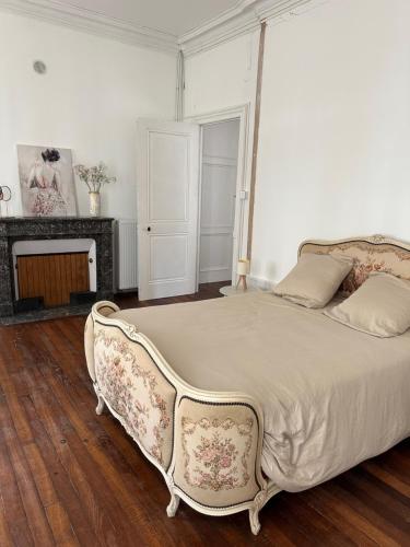 - une chambre avec un grand lit et une cheminée dans l'établissement Maison style Haussmannien centre ville, à Gray