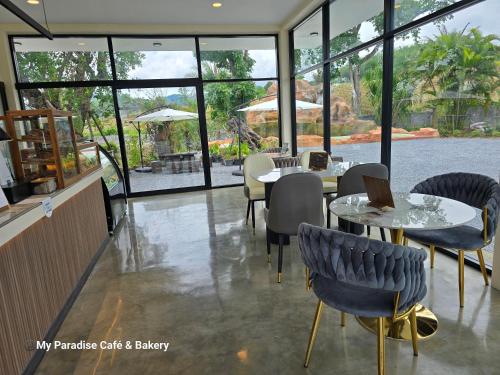 a restaurant with tables and chairs and windows at My Paradise Chiang Rai in Ban Doi Hang