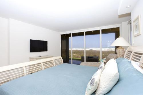 a bedroom with a blue bed and a television at Sea Vista in South Padre Island