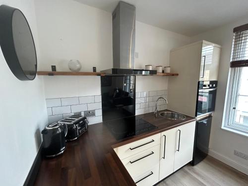 a kitchen with white cabinets and black appliances at The Hideaway - 2-Bedroom Apartment with outdoor terrace & free parking in Lancaster