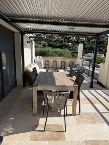 une table et des chaises en bois sur une terrasse dans l'établissement Vue mer et chant des oiseaux, à Cavalaire-sur-Mer