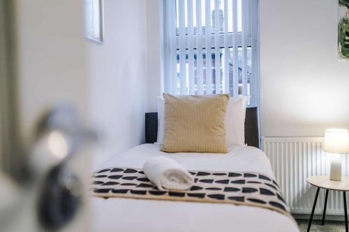 a room with a bed with a pillow and a window at Bright & Comfy 4-Bedroom House 10 mins to City by Rest&Recharge in Manchester