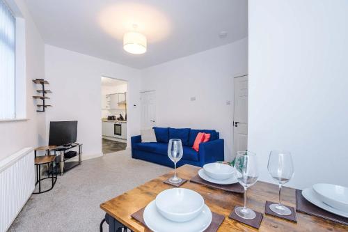 a living room with a table and a blue couch at Bright & Comfy 4-Bedroom House 10 mins to City by Rest&Recharge in Manchester