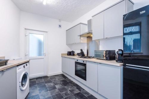 a kitchen with white cabinets and a washer and dryer at Bright & Comfy 4-Bedroom House 10 mins to City by Rest&Recharge in Manchester