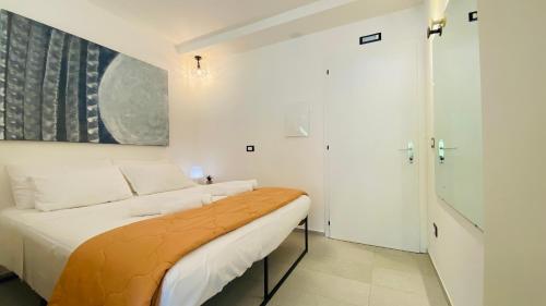 a white bedroom with a bed and a painting on the wall at LAC Holiday Apartment in Calceranica al Lago