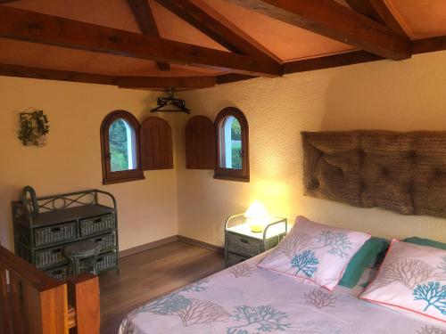 une chambre avec un lit, une table et des fenêtres dans l'établissement Un îlot tropical en Cévennes, à Saint-Privat-des-Vieux