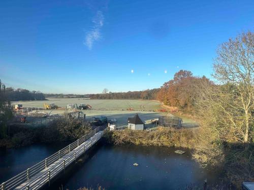 a bridge over a river next to a field at The Stables & Silos in Braintree
