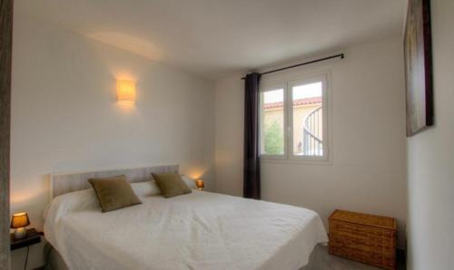 una camera da letto bianca con un letto e una finestra di Village Cargèse 2 a Cargèse