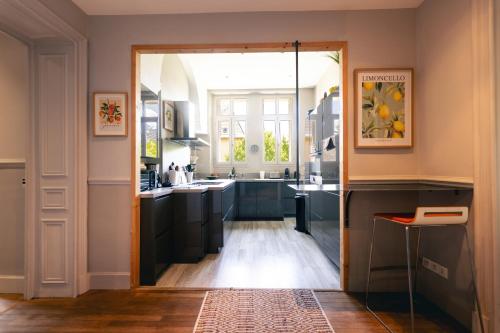 une cuisine avec une porte menant à une cuisine avec des armoires noires dans l'établissement Appartement 130m2 dans villa Mexicaine, à Barcelonnette