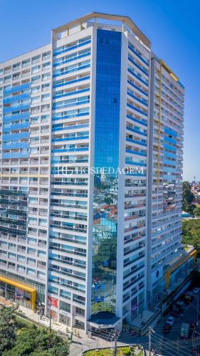 a tall white building with blue windows at 0610 - Studio alto padrão in Guarulhos