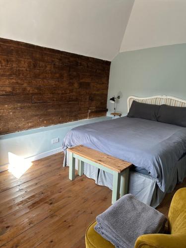 a bedroom with a bed with a wooden wall at The Stables & Silos in Braintree