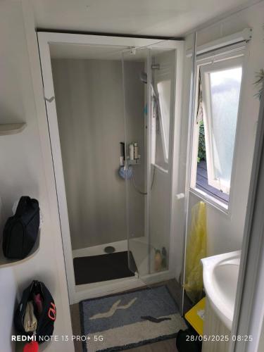 La salle de bains est pourvue d'une douche, d'une fenêtre et d'un lavabo. dans l'établissement Mobil home Le castellas, à Sète