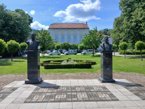 two statues in a park with a building in the background at Tri srca in Banja Koviljača
