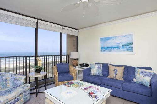a living room with blue couches and a balcony at Sea Vista in South Padre Island