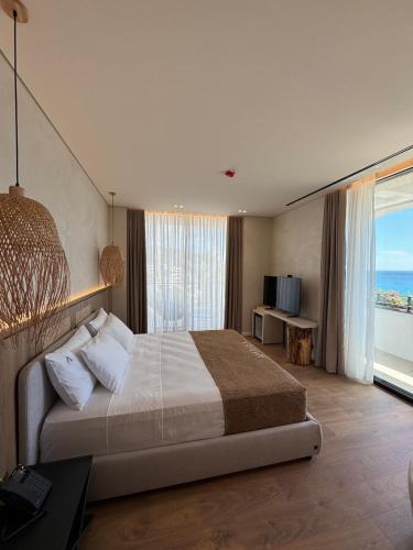 a bedroom with a large bed with a view of the ocean at Amarea Boutique Hotel in Dhërmi