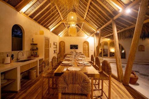 a long dining room with a long table and chairs at Villa Keluarga in Gili Air