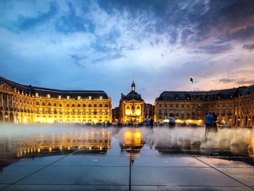 Un gran edificio con una fuente delante. en La maison de Léandre - Medoc, en Saint-Seurin-de-Cadourne