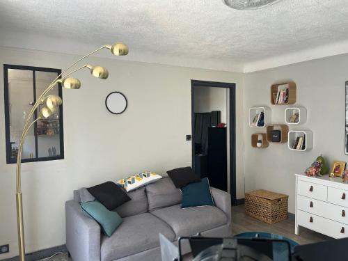 - un salon avec un canapé gris et une lampe dans l'établissement Appartement charmant dans une résidence calme, à Perpignan