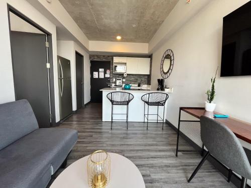 a living room with a couch and chairs and a kitchen at Lux at 15, Pool, Gym and Stylish City Stay in Hatillo