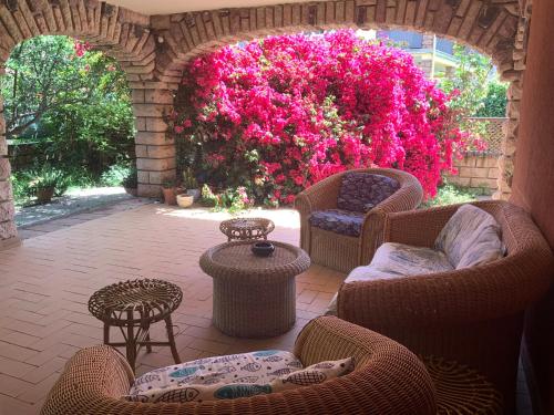 a patio with chairs and tables and pink flowers at Abbratzu Guest House - Sardinian style and garden in Bosa