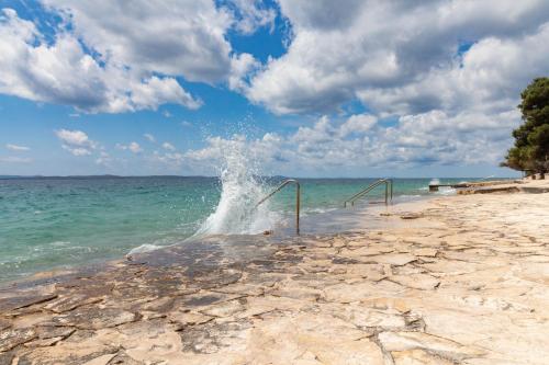 a wave hitting the shore of the beach at Seaside Apartments Slavica in Petrcane
