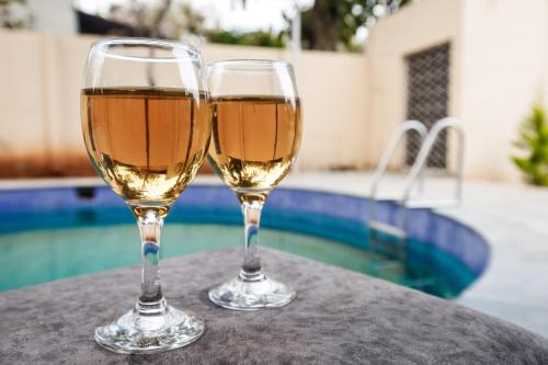 DenkanikottaiにあるRustica Villa By Secret Turtle 7BHK 2Pvt Pool Projectorのスイミングプールの近くのテーブルに座ったワイン2杯