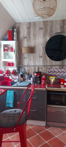 une cuisine avec une chaise rouge devant un comptoir dans l'établissement Le paradis bleu, à Bosville