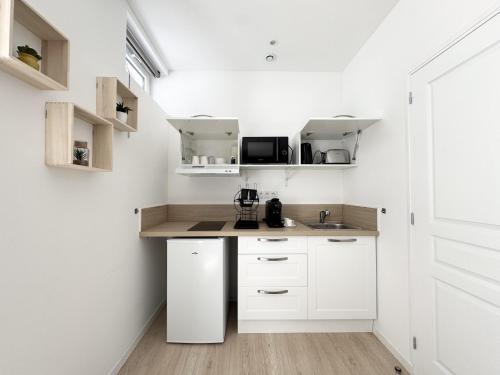 une petite cuisine avec des armoires blanches et un évier dans l'établissement Appartements Cosy & Chic- Hyper Centre AGEN, à Agen
