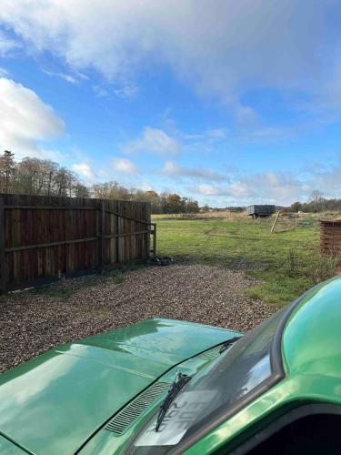 a green car parked in a field next to a fence at The Stables & Silos in Braintree