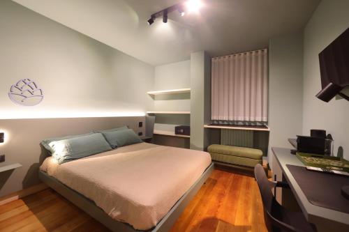 a small bedroom with a bed and a desk at La Pigna Suites in Verona