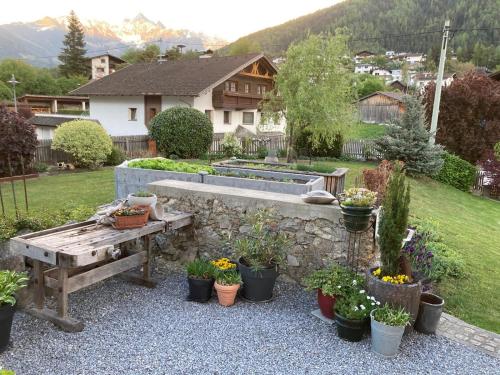a garden with a stone wall and a bench and potted plants at Gästehaus Köll in Roppen