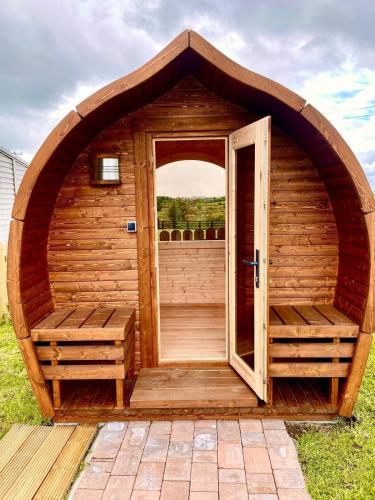 a wooden sauna with an open door in the grass at Heather Cottage and Shepherds Hut in Knock
