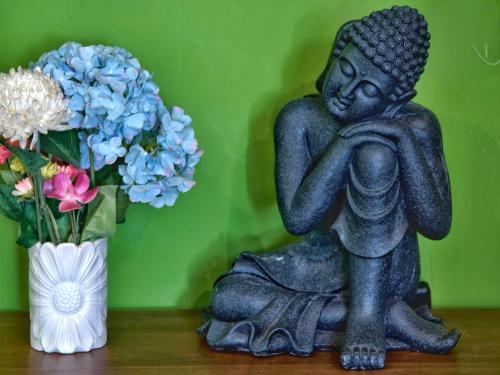 a statue sitting on a table next to a vase of flowers at Tana Mysterious garden in Panglao