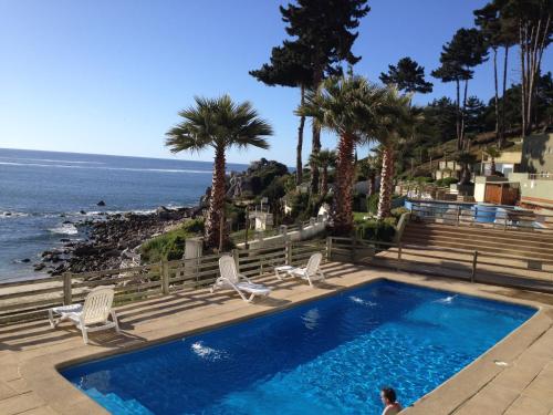 una piscina junto al océano con palmeras en Pinares del Canelillo en Algarrobo, en Algarrobo