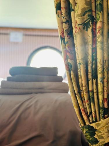 a curtain on a bed with a stack of pillows at The Stables & Silos in Braintree