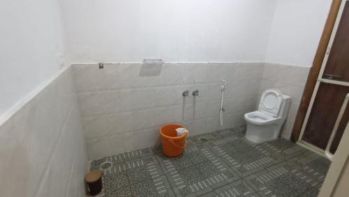 a bathroom with a toilet and a trash can at Sugarcane Homestay in Attigundi