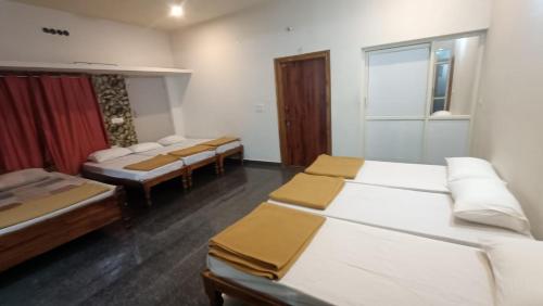 a room with three beds and a row of chairs at Sugarcane Homestay in Attigundi
