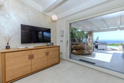 a living room with a tv and a large window at VILLA AMIRA Porto Cervo con vista Mozzafiato sul Mare,Piscina Privata,WELLNESS & SPA in Liscia di Vacca